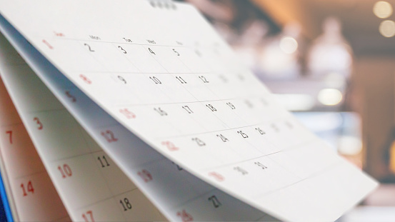 Close up white paper desk calendar with blurred bokeh background appointment and business meeting concept